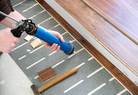 ein Fertigparkett oder -Laminat wird verlegt, dazu wird auf einer Trittschalldämmung ein Klebstoff aufgebracht 