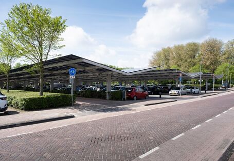 auf einem Parkplatz stehen Autos, die mit Dächern aus Photovoltaikmodulen überdacht sind