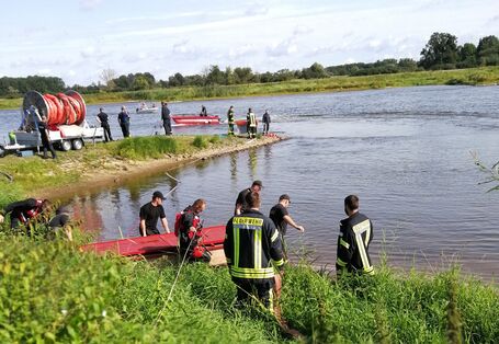 Feuerwehrleute mit Booten an und auf einem Fluss im Einsatz