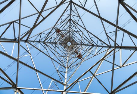Blick von unten in das Stahlgestänge eines Strommastes einer Hochspannungsleitung