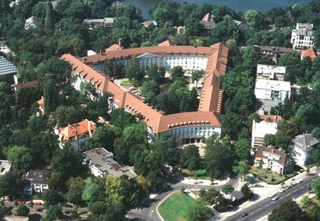 Triangular building complex with green inner courtyard nestled in an urban district with many trees