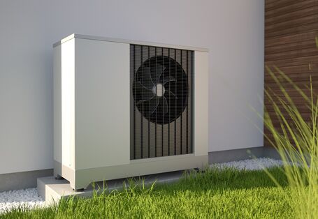 Aggregat einer Wärmepumpe vor einer Hausfassade