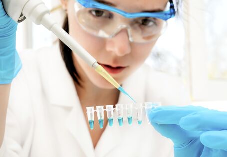 Junge Chemielaborantin füllt Flüssigkeitsproben ab.