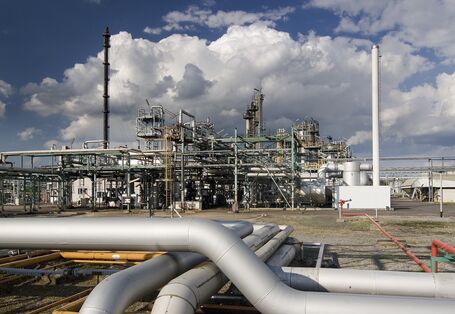 Nahaufnahme einer Chemieanlage vor wolkigem Himmel