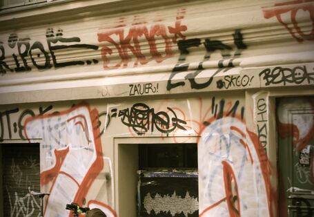 Ein Mann spielt aus dem Fenster seiner Wohnung heraus Trompete, auf dem Bürgersteig darunter schaut ein kleiner Junge mit seinem Fahrrad hoch zu dem Mann im ersten Stock und hört ihm zu.