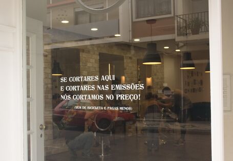 Aufschrift auf dem Schaufenster: „Ihr kommt mit dem Rad zu uns und senkt damit die Emissionen, dann senken wir den Preis Eures Haarschnitts“