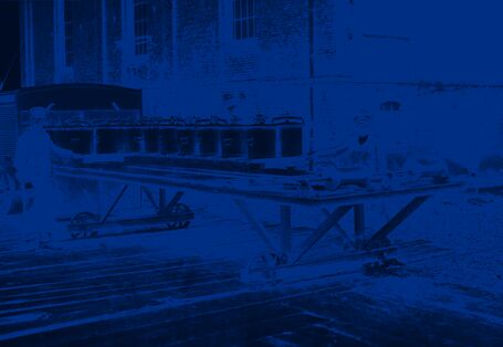 Zwei Männer tauschen Eimer auf einem auf Schienen laufenden Wagen aus.