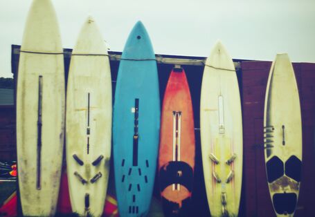 Sechs Surfbretter lehnen an einer Garage