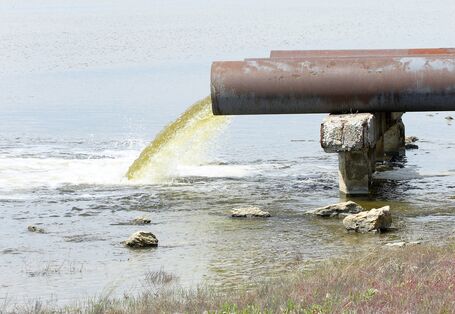 Aus einem Rohr fließt Abwasser in ein Gewässer