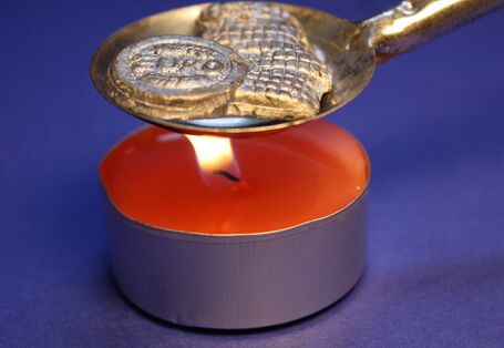 red candle with a spoon for lead pouring