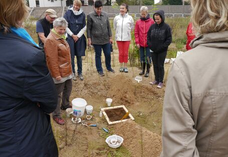 Menschen stehen um ein Bodenfenster herum