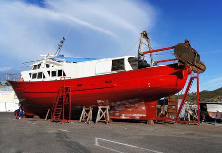 rotes Fischerboot liegt in der Werft, wird neu angestrichen