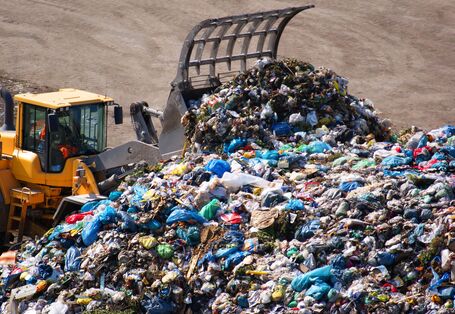 Ein Bagger schiebt den Müll der Abfalldeponie zusammen