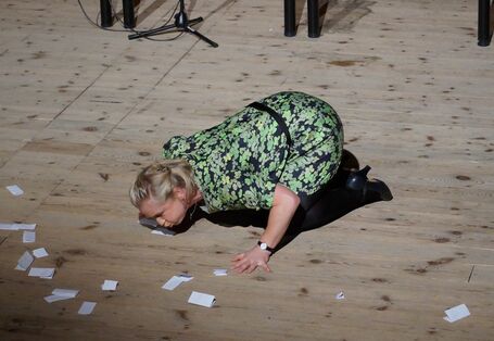 auf dem Boden kniende Frau pustet Papier