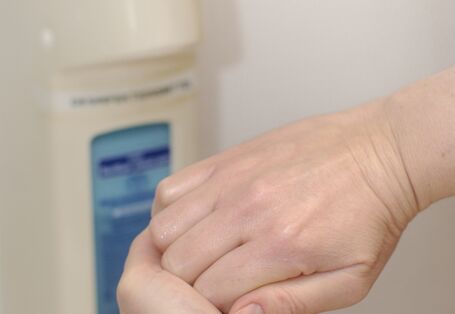 Hände verreiben das Desinfektionsmittel aus dem Spender.