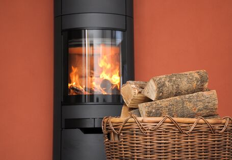 Kaminofen mit Feuer und Brennholzkorb