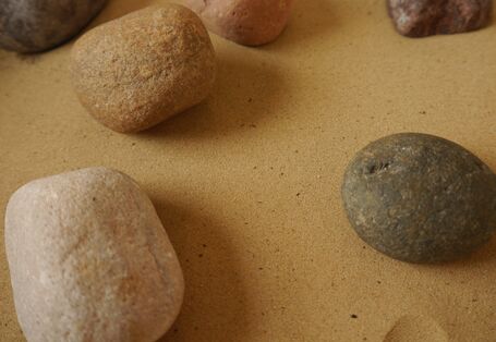 Steine liegen auf hellem Sand.