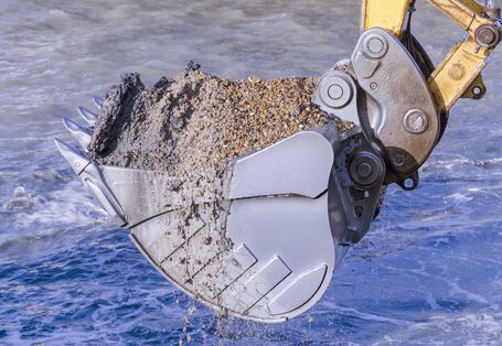 Excavator bucket with sediment in a river