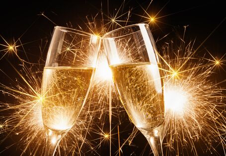 zwei Sektgläser vor goldenem Feuerwerk