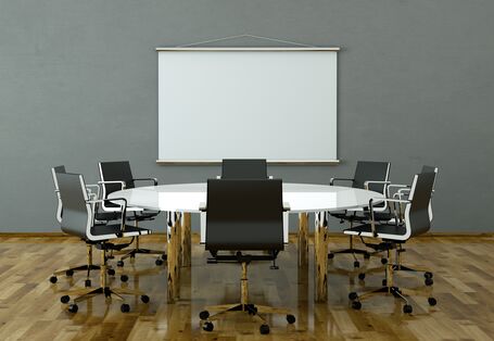 Konferenzzimmer mit hölzernem Bodenbelag, auf dem Tisch und Stühlen stehen