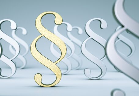 goldenes Paragraphenzeichen umgeben von grauen und weißen Paragraphenzeichen