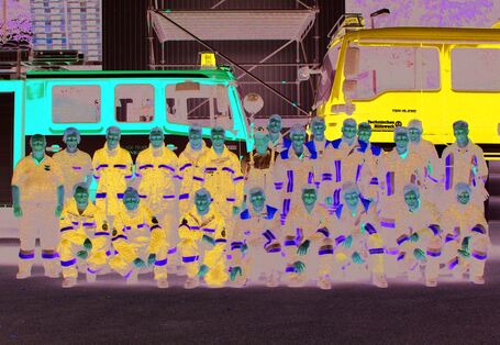 Einsatzkräfte in Uniformen des THW und einer Feuerwehr als Gruppenfoto vor ihren Einsatzfahrzeugen.