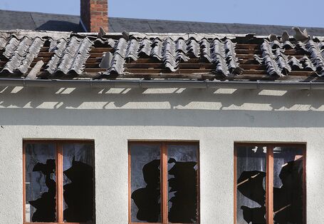 Gebäude mit zerbrochenen Fensterscheiben und teilweise abgedecktem Dach.