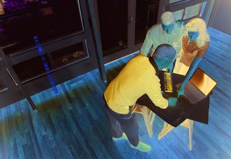 Gestaltung einer Wohnung: Einrichtungspläne und Laptop. Drei Personen: Innenarchitekt und ein junges Paar (Mann und Frau), die sich mit Einrichtungsplänen der Wohnung beschäftigen.