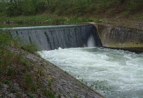 Querbauwerk in einem Fluss - Wasser fließt senkrecht eine Wand herunter