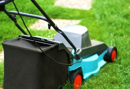 Ein elektrischer Rasenmäher, der auf einer grünen Wiese steht