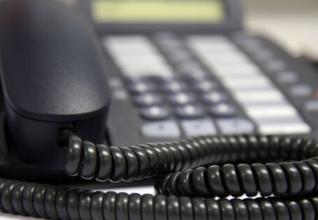 Nahaufnahme von einem schwarzen Telefonhörer mit Schnur