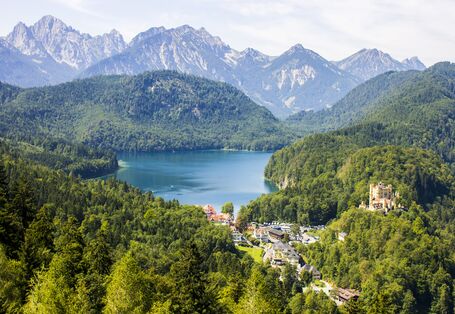Blick auf einen Bergsee mit Bergen darum und einem blauen Himmel.