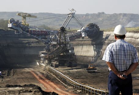 Ein Mann mit Bauhelm schaut auf einen Tagebau.