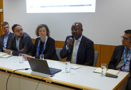 Ein Foto von der Konferenz: Fünf Personen sitzen hinter einem Konferenztisch.