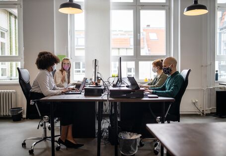 Eine Frau trägt einen Mundschutz und guckt aus dem Fenster