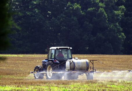 Ein Traktor sprüht Pflanzenschutzmittel auf ein Feld.