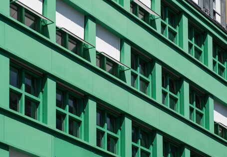 Eine Hausfassade mit Fenstern, die beschattet werden.