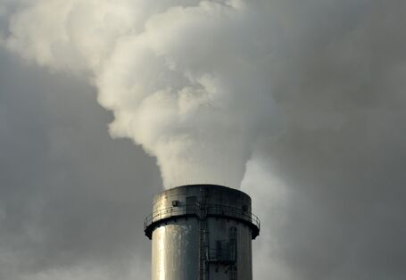 Ein rauchender Schornstein vor bewölktem Himmel.