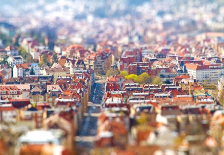 Eine Stadt aus der Luft, es sind Dächer und eine Straße zu sehen.