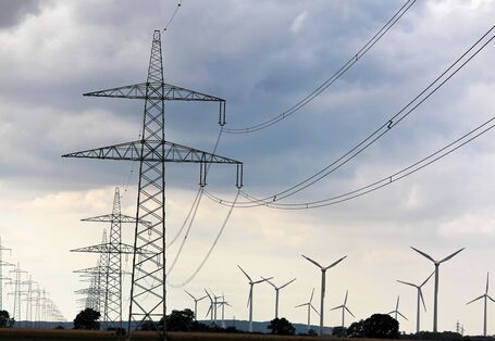 Ein Strommast mit Leitungen vor blauem Himmel.