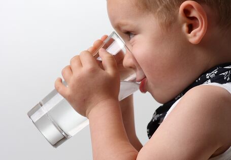 Ein Kind trinkt aus einem Glas.