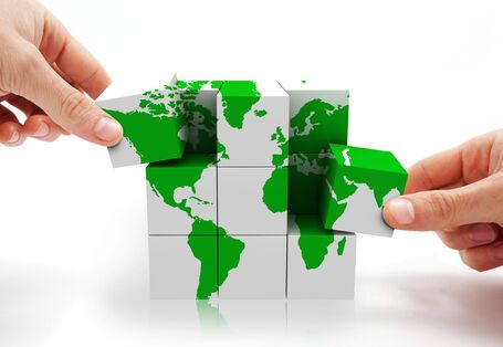 Zwei Hände mit Würfeln, die die Weltkarte abbilden.