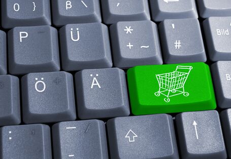 A computer keybord with a green button with a shopping cart.