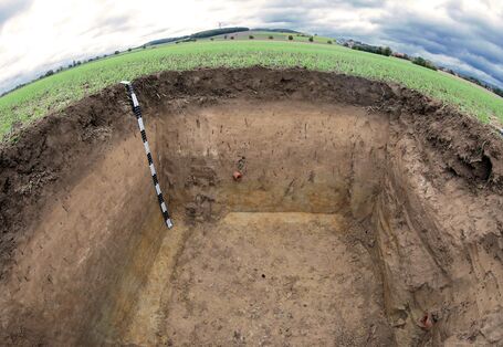 Großes ausgehobenes Loch auf einer Wiese; Bodenprofil vom Lössboden zu sehen