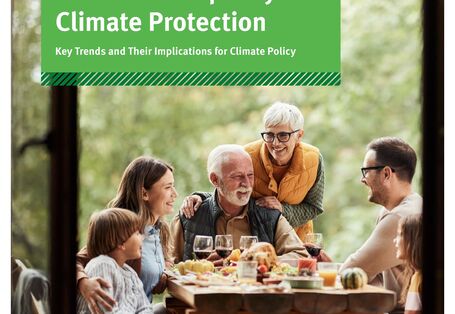 Menschen sitzen um einen gedeckten Tisch im Freien