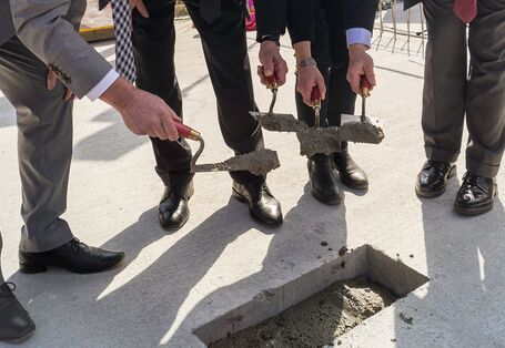 UBA-Präsidentin Maria Krautzberger und Umweltstaatssekretär Jochen Flasbarth stehen auf dem Fundament der Baustelle und spachteln das letzte Loch mit der Zeitkapsel zu.