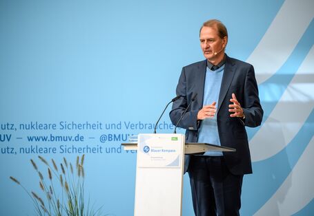 Präsident des Umweltbundesamtes Dirk Messner hat gemeinsam mit der Bundesumweltministerin die besten Projekte ausgezeichnet und hielt eine Rede am Rednerpult, wie auf dem Bild zu sehen.