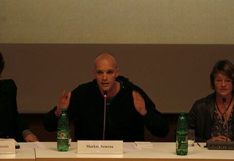 Mit erhobenen Händen spricht der Podiumsdiskutant Marcus Semrau zum Publikum.