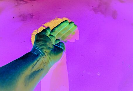 The picture shows the palm of a hand stroking the surface of a water body.