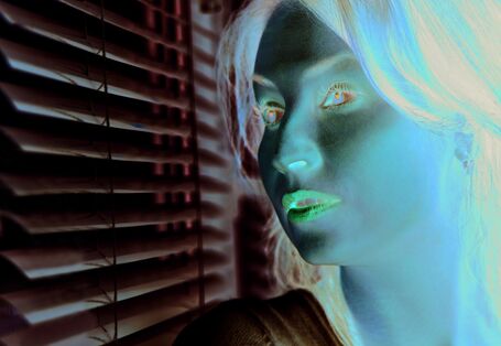 The picture shows a woman’s head and shoulders while she looks sceptically out of a window. The window is part-shaded by an indoor blind.